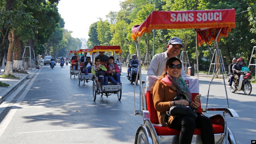 中國遊客坐在三輪人力車上觀賞河內街景。
